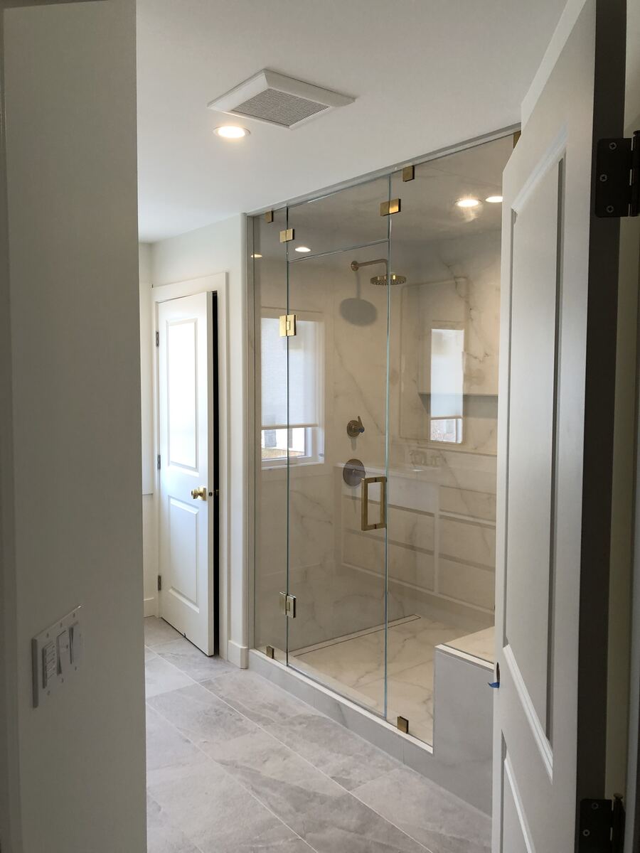 Frameless glass shower with recessed and marble tile lighting